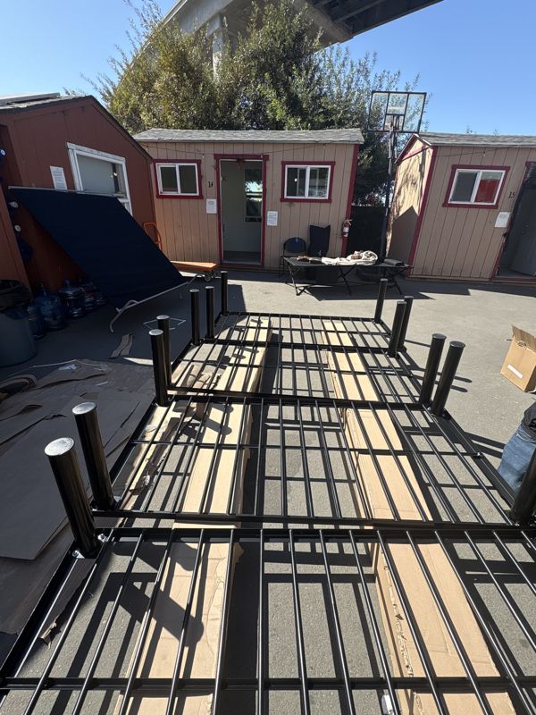Steel platform beds staged outside Oakland tiny home cabins